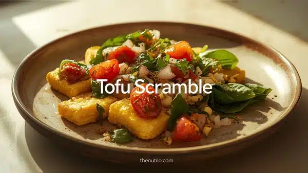 “Tofu scramble with spinach and tomatoes served on a plate.”