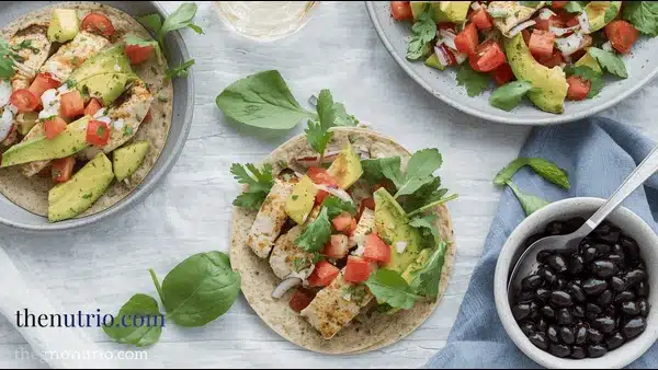 Whole-wheat tortillas filled with pan-seared white-fish strips, avocado-tomato-onion-cilantro salsa, side bowl of black beans on outdoor dinner table
